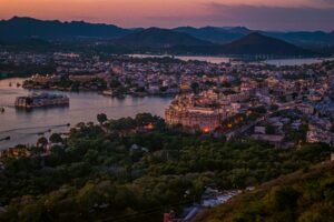 Stunning aerial view of Udaipur cityscape at twilight, featuring lakes and historic architecture.