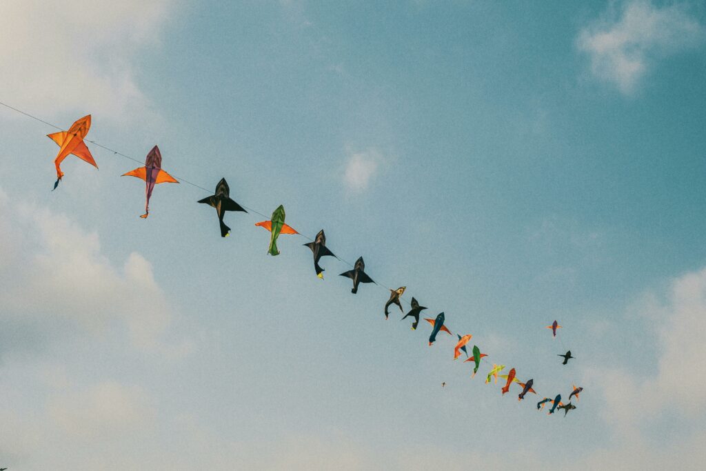A vibrant array of kites soaring in a clear blue sky, perfect for a sunny day.